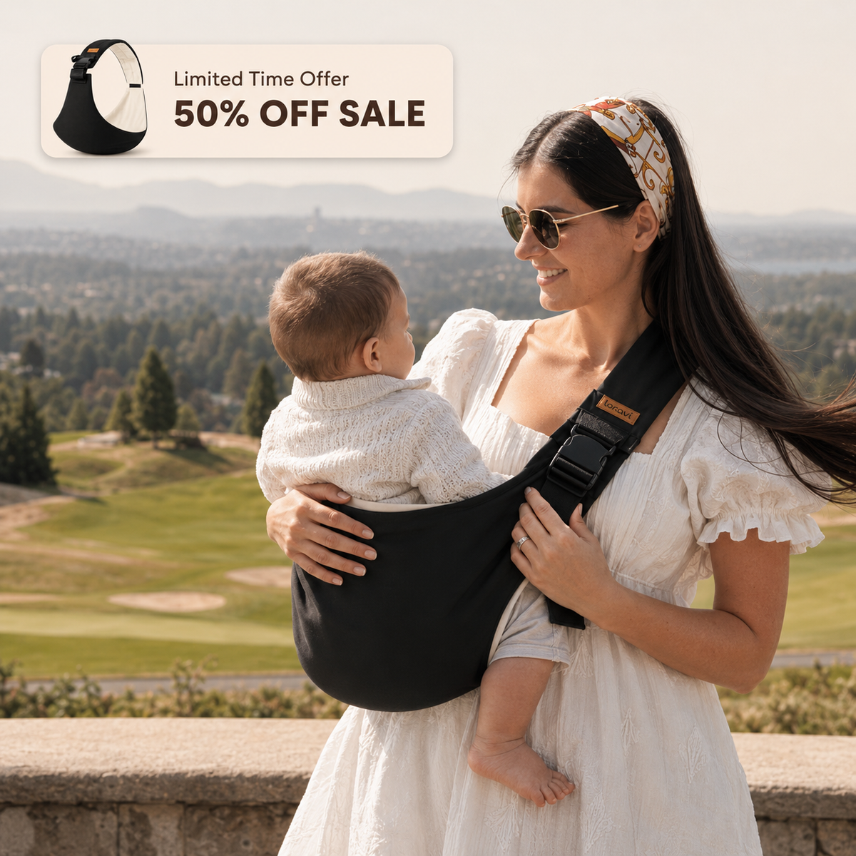 Mother carrying her baby in the Loravi Sling outdoors with a scenic hilltop view